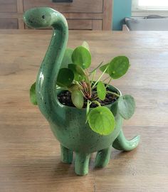 a green dinosaur planter sitting on top of a wooden table