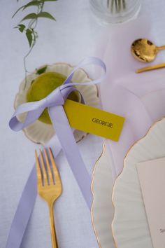 a table setting with place cards, silverware and gold utensils on it