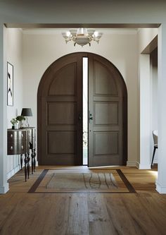 an entryway with two wooden doors and a rug on the floor in front of it