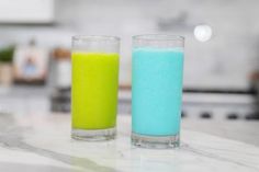 two glasses filled with different colored liquids on a counter top next to each other