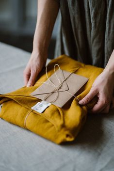 a person is holding a piece of paper and string on top of a yellow bag