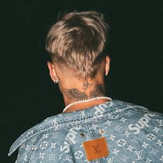 the back of a man's head, with tattoos on his neck and chest