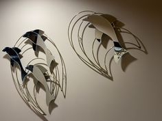 two metal birds sitting on top of a wall next to each other in the shape of circles