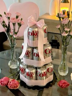 a cake made out of cans and flowers on a table with roses in vases