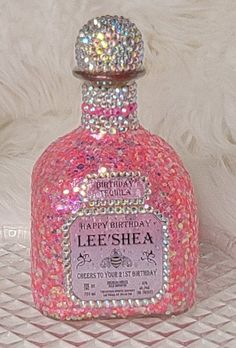 a pink bottle filled with lots of sparkles on top of a white tablecloth