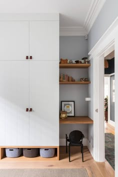 an empty room with white cabinets and wooden shelves on either side of the closet door