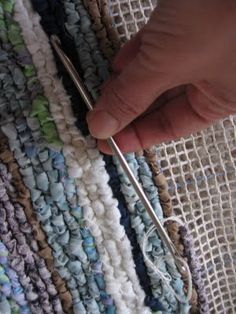 someone is crocheting together on a rug with yarn and scissors in their hand