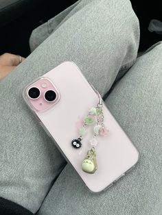 an iphone case with two charms attached to it sitting on a person's lap