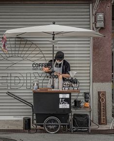 a man standing under an umbrella selling coffee