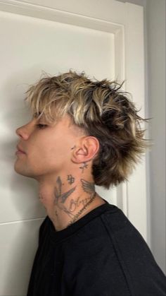 a man with tattoos on his neck standing in front of a door