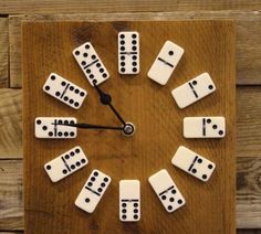 a clock made out of dominos sitting on top of a wooden table next to a wall