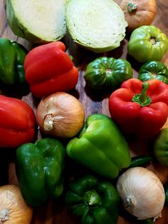 many different types of vegetables on a cutting board with onions, peppers, and garlic