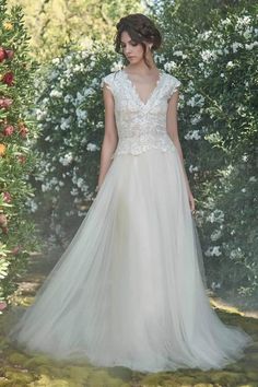 a woman standing in front of flowers wearing a wedding dress