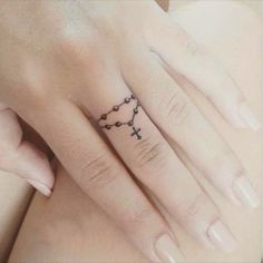 two hands with tattoos on their fingers, one has a cross and the other has a heart