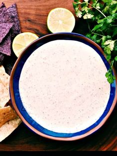 a bowl of dip surrounded by tortilla chips, cilantro and lime