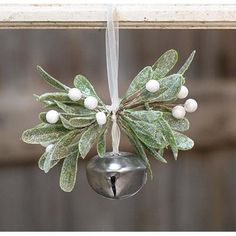 an ornament hanging from the side of a window with leaves and berries on it