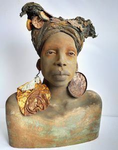 a woman's head is covered in gold and has two coins hanging from her ear