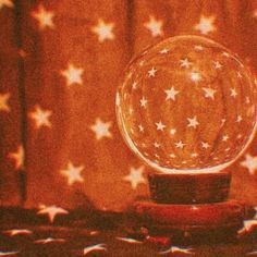 a glass ball with stars on it sitting on top of a wooden table next to a curtain