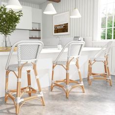 three white wicker bar stools sitting in front of a kitchen counter