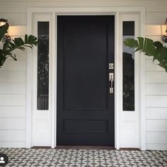 a black front door with white trim and two planters