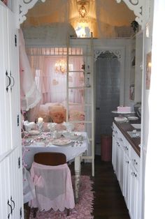 a small kitchen with white cabinets and pink decor on the walls, along with a dining table set for four