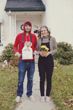 a man and woman standing in front of a white house with a teddy bear on his backpack