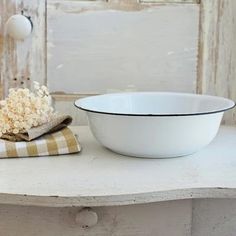 a white bowl sitting on top of a table next to a towel and a vase