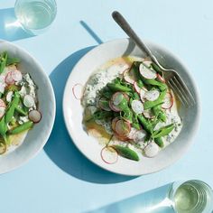 two white plates filled with food next to glasses and utensils on a blue surface