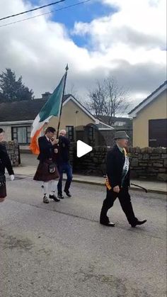 some people in kilts are walking down the street with an irish flag on their head