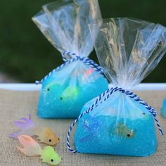 two bags filled with blue soap sitting on top of a table next to small plastic fish