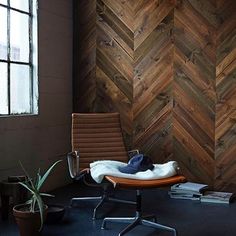 an office chair sitting in front of a wall made of wooden herringbone planks