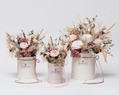 three white buckets with flowers in them