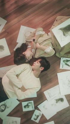 two people laying on the floor surrounded by pictures