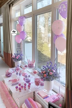 a table with pink and purple balloons, cake, candy bars, flowers and other decorations