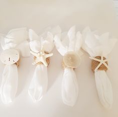 three pieces of white cloth tied together with seashells and starfish on them