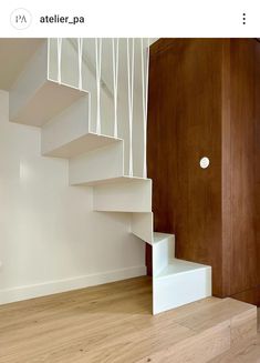 there is a white stair case next to the wooden floor in this room with wood paneling