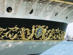 the side of a large boat with gold designs on it's hull and sides