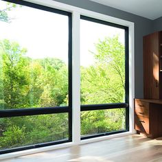 an empty room with large windows overlooking trees