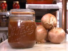 some onions are sitting on a counter next to a jar with something brown in it