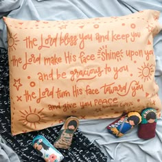 an orange pillow with words written on it next to two small toy dolls and a pair of slippers