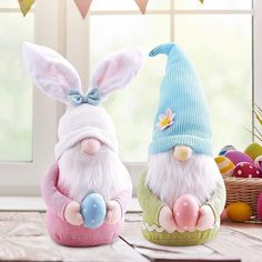 two stuffed animals sitting next to each other on top of a wooden table in front of easter eggs