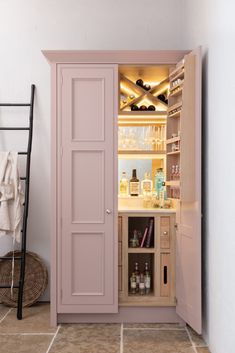 an open cabinet in the corner of a room next to a ladder and towel rack