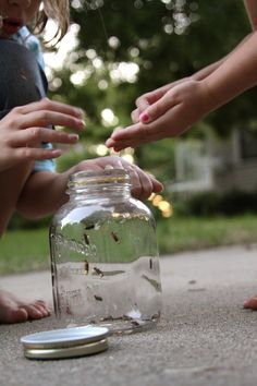 two adults and one child reaching for something in a jar on the ground next to a coin