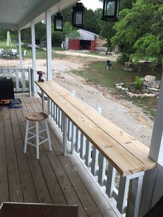 the porch is covered with white railings and wooden flooring, along with two bar stools