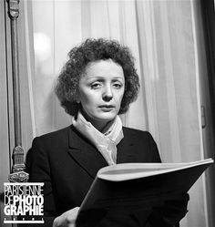 a woman reading a book while wearing a suit