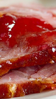 two slices of ham sitting on top of a plate covered in ketchup and jelly