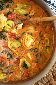 a bowl filled with pasta and spinach soup on top of a woven place mat