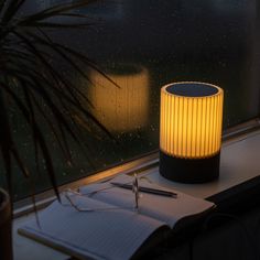 a lamp sitting on top of a window sill next to a pen and notebook