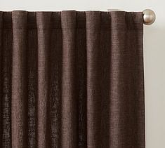 a brown curtain hanging from the side of a window with metal rods on top of it