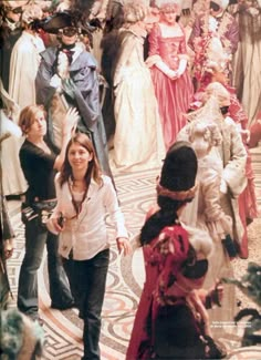 a group of people dressed up in fancy clothing walking down a hall with other people